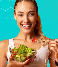 Mulher sorridente com um pote de salada em uma das mãos e um garfo em outra. A imagem reforça a presença de biotina e cisteína da fórmula de Spax Hair & Nails.