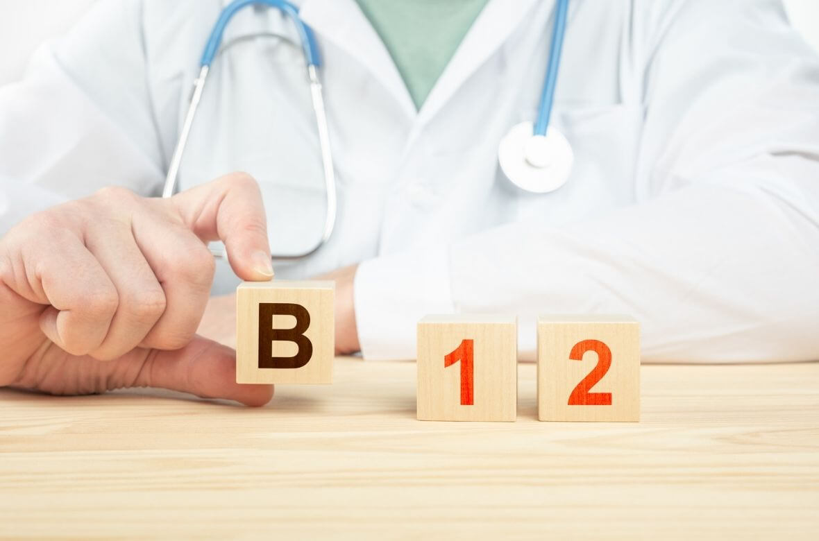 Mão de médico mostra três cubos de madeira que compõe a escrita B12, uma das 12 melhores vitaminas para cabelo e unha