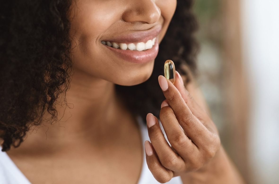 Mulher com cápsula vitamínica na mão prestes a ingerir para fortalecer as suas unhas